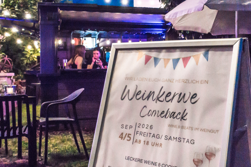 Großes Veranstaltungsschild mit der Bar im Hintergrund