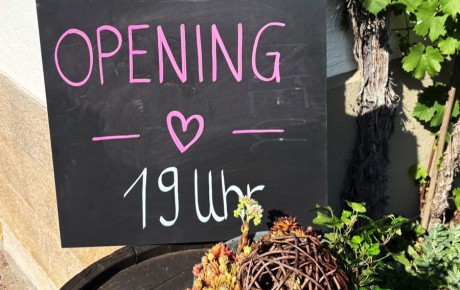 Tafel mit der Beschriftung "Opening - 19 Uhr"