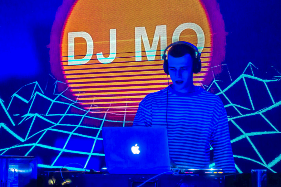 Discjockey mit farbiger Projektion im Hintergrund